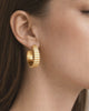 Model wearing gold-plated ribbed hoop earrings with modern textured design