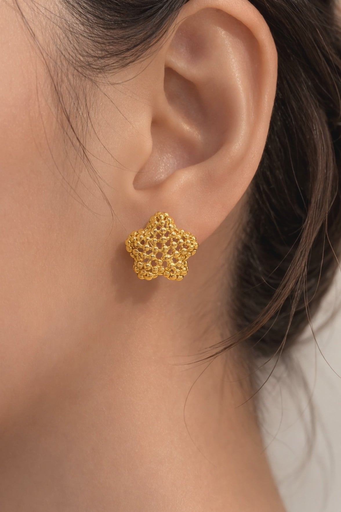 Close-up gold-plated bubble flower stud earrings with textured design