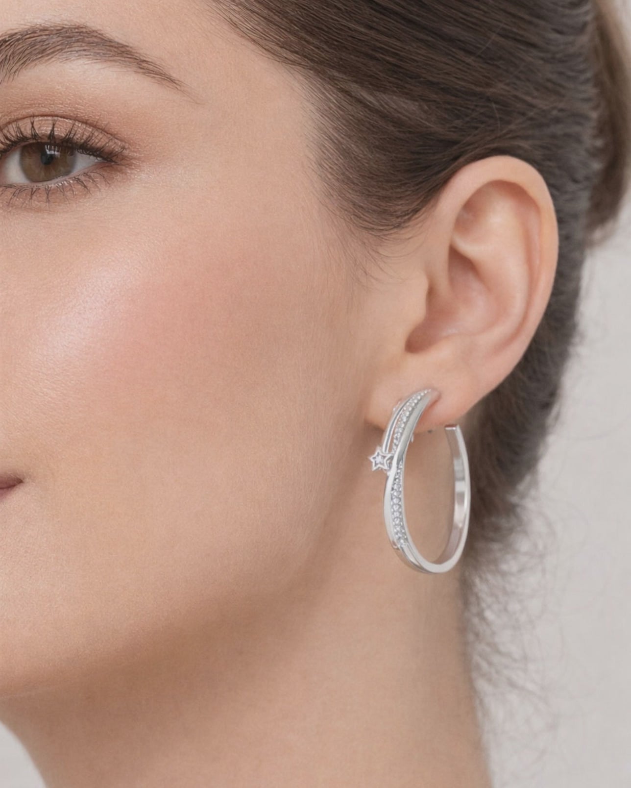 Silver star hoop earrings with crystal detail worn on ear minimalist style