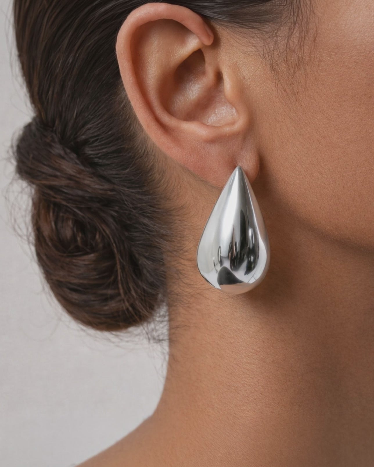 Silver teardrop statement earrings on ear minimalist modern jewelry style
