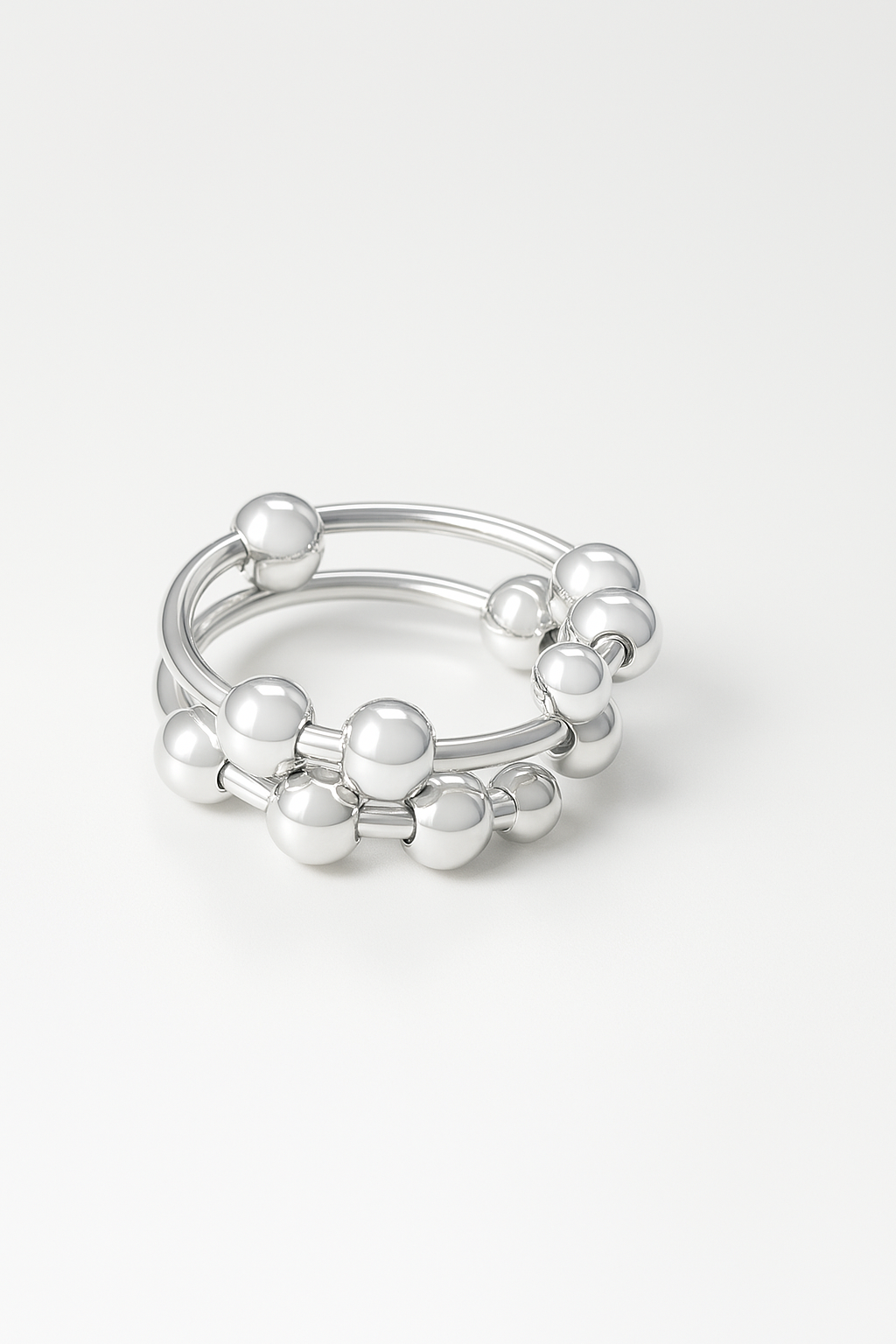 silver-plated sculptural ring with double bands and polished ball accents on white background