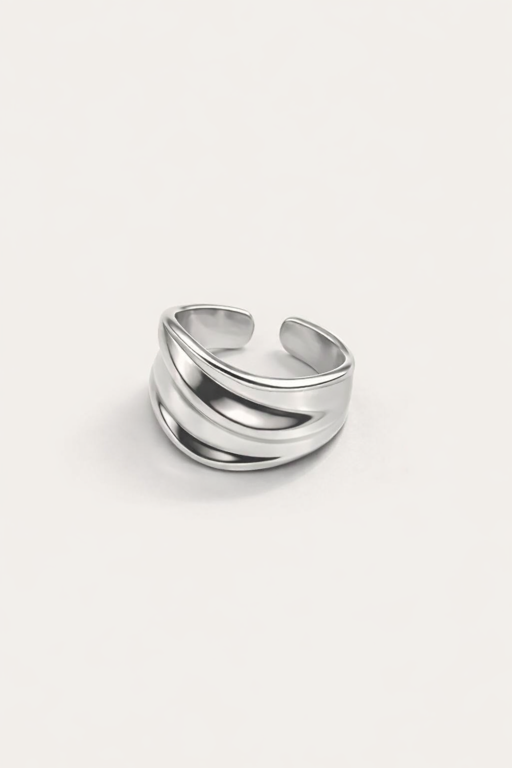 Silver-plated open cuff ring with layered sculptural bands, modern minimalist statement ring on neutral background