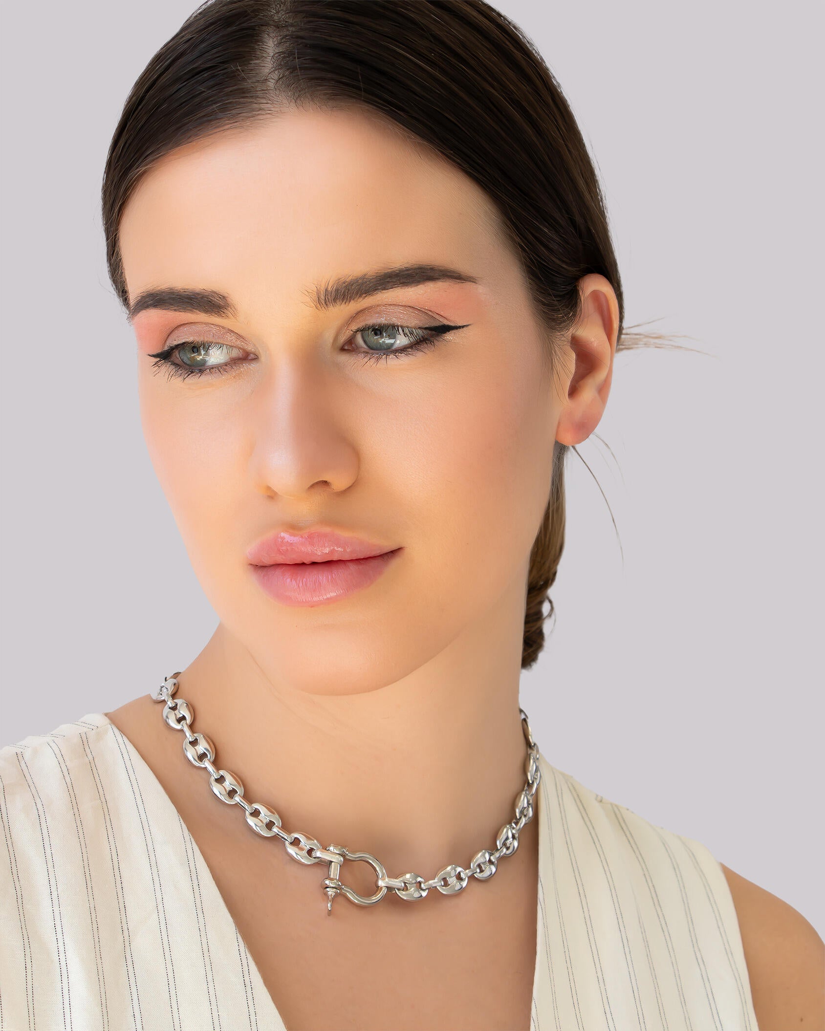 Model wearing chunky silver collar necklace with sculpted links and industrial-style shackle clasp.
