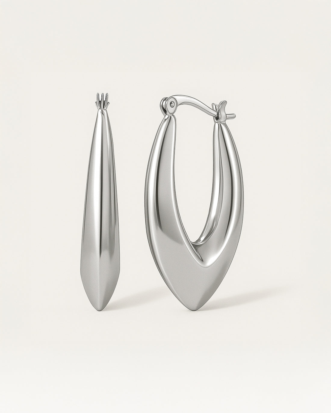 Close-up of sculpted silver hoop earrings in bold marquise teardrop shape with latch-back closure