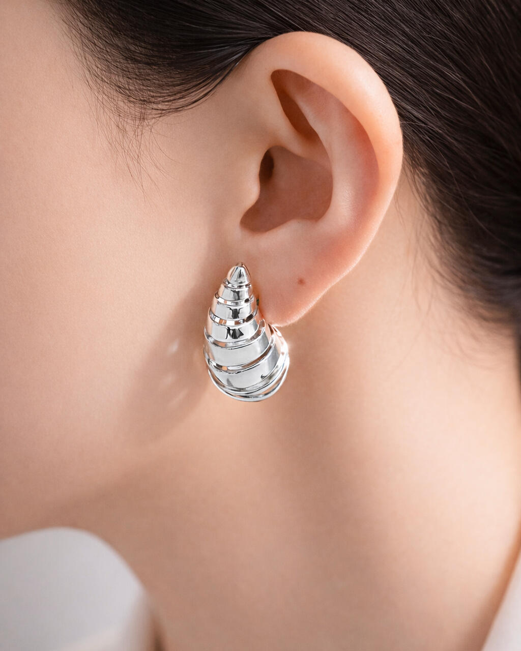 silver-plated shell spiral stud earrings, sculptural spiral design, minimalist jewelry on white background