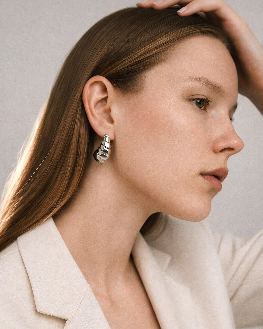 model wearing silver-plated shell spiral stud earrings, sculptural spiral design, minimalist jewelry side profile
