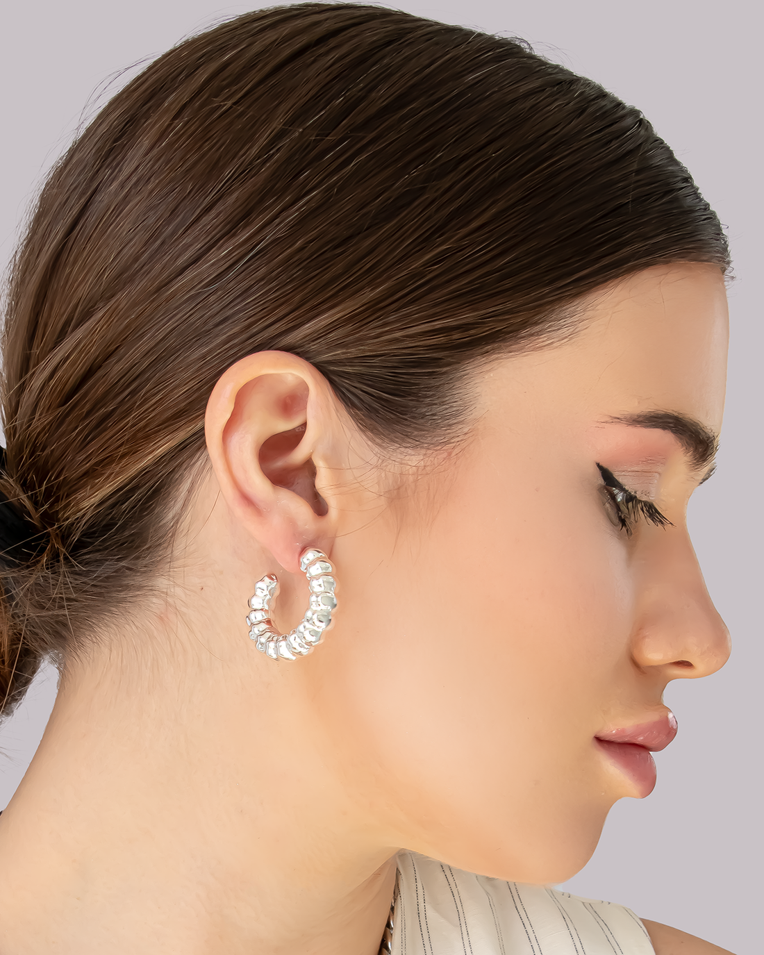 Model wearing silver hoop earrings with chunky rounded bead-like texture – bold sculptural statement design.