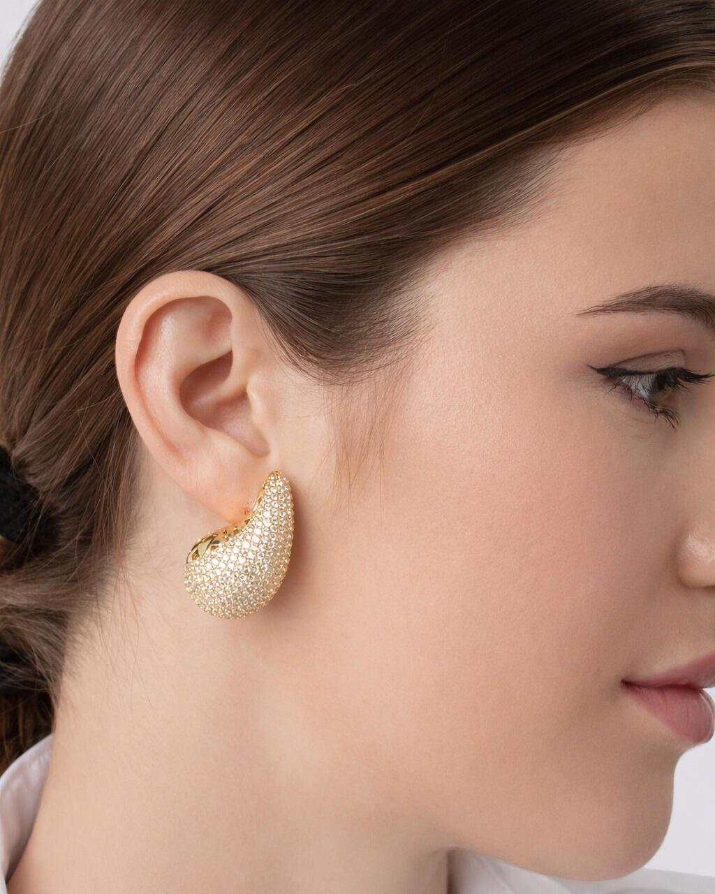 Gold teardrop stud earring with sparkling textured surface, featuring a sculptural teardrop design by Jadejuri