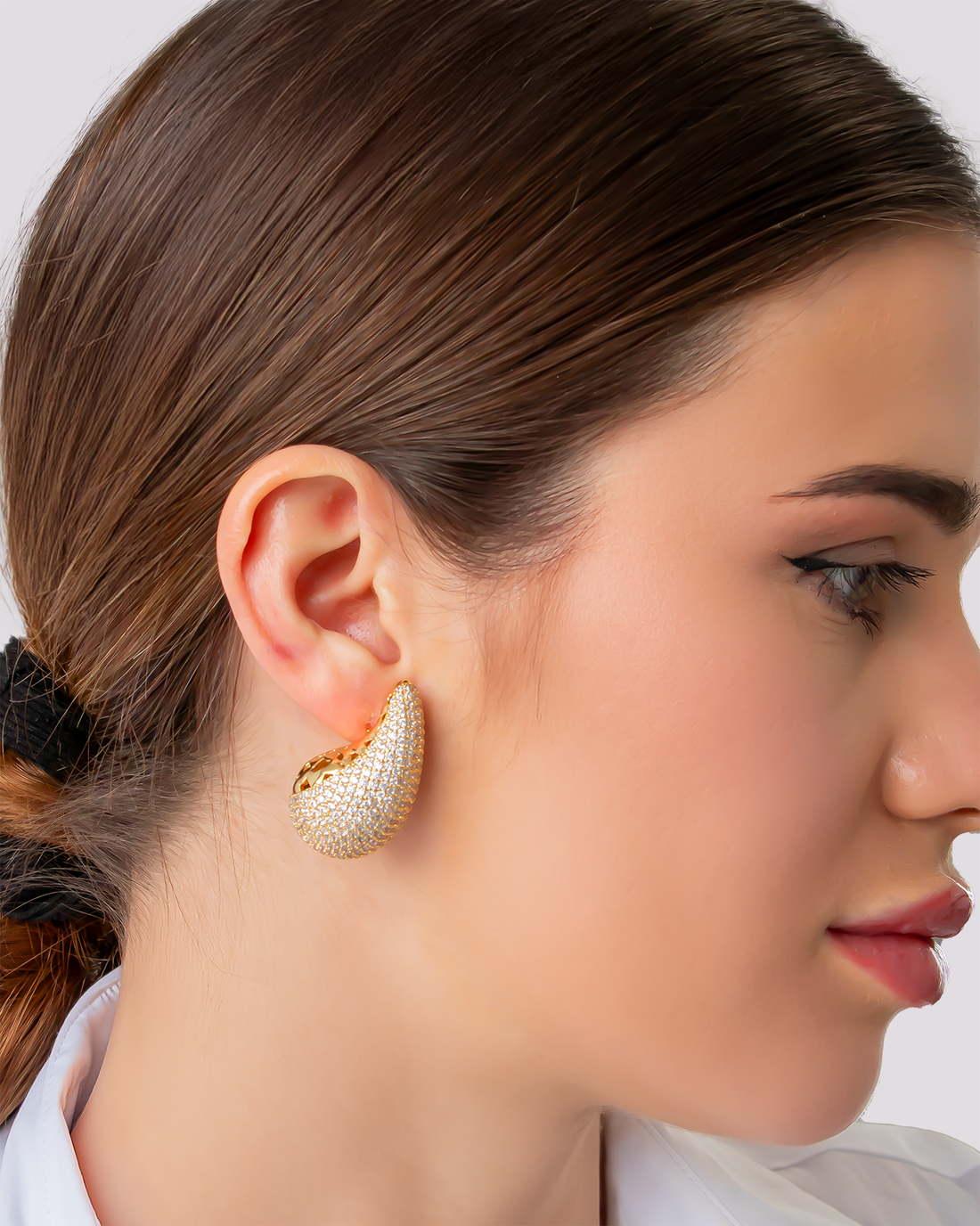 gold teardrop stud earrings paved with shimmering zircon stones close up model