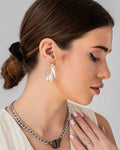 Model wearing sculptural silver twisted hoop earrings with wave-like form – bold, modern stud jewelry design.
